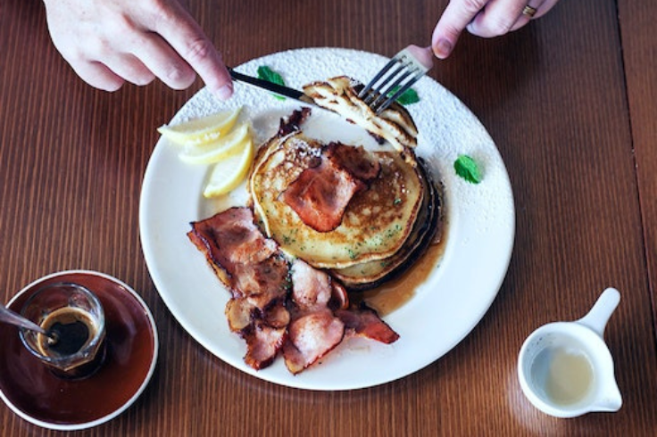 Aerial view of hands cutting into pancakes