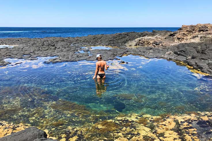 A woman standing in the clear water of Bushrangers Bay Beach