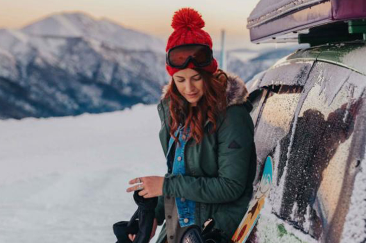 girl gets ready to snowboard at mount hotham next to jucy camper