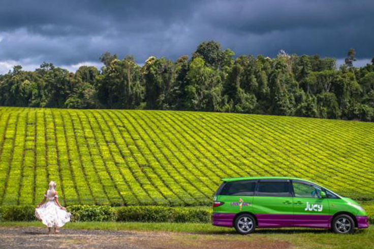 Girl looking out a field with a JUCY campervan