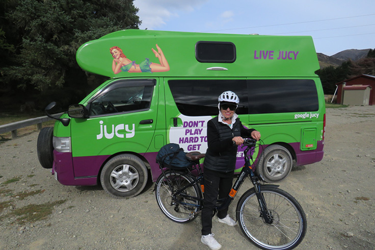 Girl on bike outside JUCY campervan