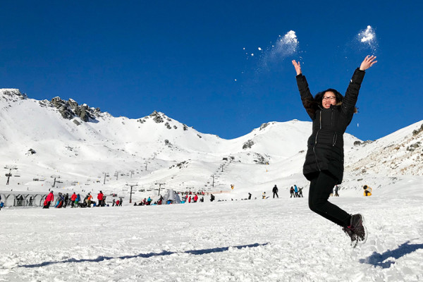 Girl in black ski gear jumping at Queenstown ski field