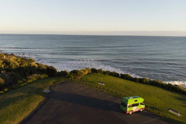 JUCY camper parked in carpark at top of hill