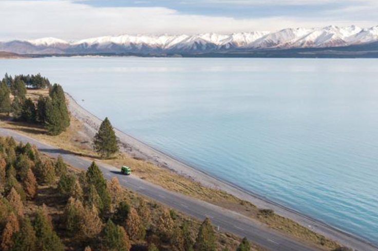 JUCY camper driving alongside snowy mountains