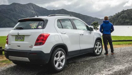 man looks on lakefront with parked suv